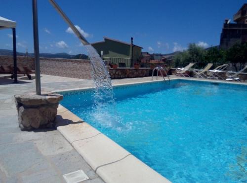 a swimming pool with a fountain in the middle at Hotel Meridiana in Arbus