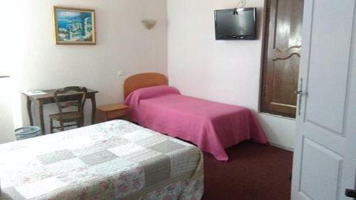 - une chambre avec une couverture rose sur un lit dans l'établissement Logis L'Auberge Basque, à Ozon