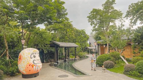 a garden with a large vase next to a walkway at Wyndham Lynn Times Onsen Wellness in La Phu