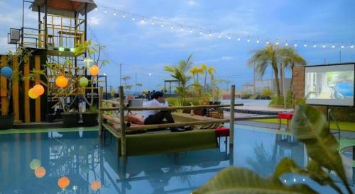 a person sitting on a bench next to a swimming pool at Grand Qin Hotel Syariah in Martapura
