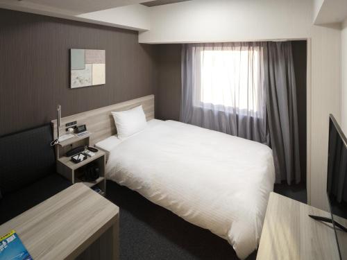a hotel room with a bed and a window at Hotel Route Inn Matsuyama -Katsuyama Dori- in Matsuyama