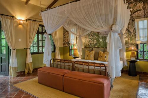 ein Schlafzimmer mit einem Himmelbett und einem Sofa in der Unterkunft Rivertrees Country Inn in Usa River