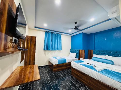 a hotel room with two beds and a flat screen tv at Hotel Welcome Airoli in Navi Mumbai