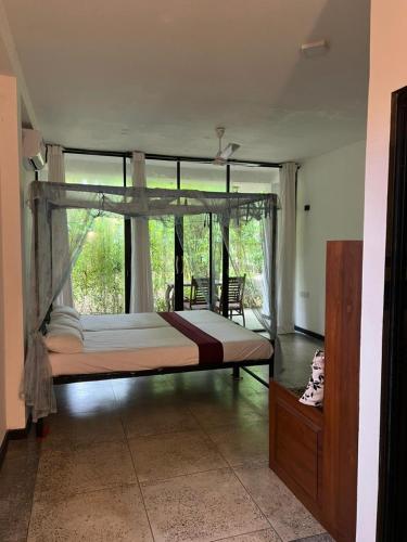 a large bed in a room with a large window at Sri Holiday House - Hikkaduwa in Hikkaduwa
