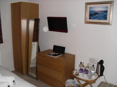 a room with a dresser and a table with a laptop at Langland Road B&B in The Mumbles