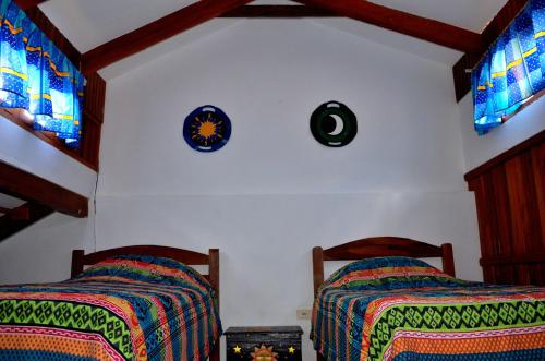 a bedroom with two beds and a clock on the wall at Posada Guasu in Samaipata