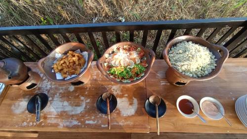 a group of bowls of food on a wooden bench at Royal Mulia by MaPan atroomS in Cigugur