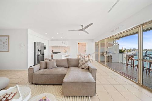 a living room with a couch and a kitchen at Serenity Waters Riverfront Retreat - Walk to Mooloolaba in Mooloolaba
