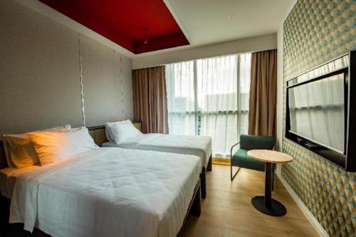 a hotel room with two beds and a television at Airdence in Kampong Sembulan