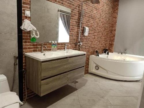 a bathroom with a sink and a tub and a brick wall at M GLOBAL HOTEL in Kampong Jeram