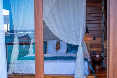 a bedroom with a canopy bed with white curtains at Naya Lodge in Mitsamiouli