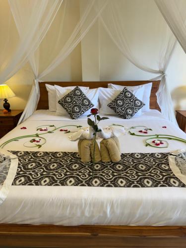 a bed with two teddy bears and flowers on it at Inang Villa ubud in Ubud