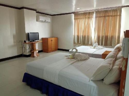 a large bedroom with two beds and a television at Jeamco Royal Hotel - Pasig in Manila