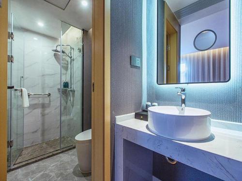 a bathroom with a sink and a glass shower at Jinjiang Inn Wuhan Linjiaohu Wanda Branch in Wuhan