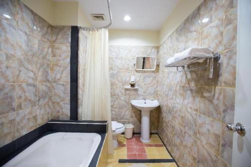 a bathroom with a tub and a toilet and a sink at Night Bazaar Place in Chiang Mai