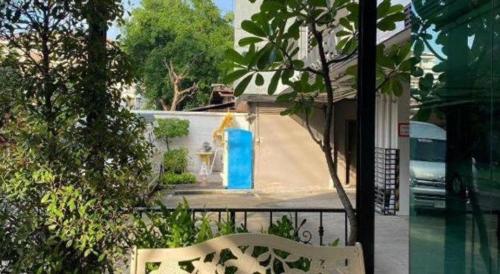 a white bench in front of a building with a blue door at Pannapat Place in Bangkok