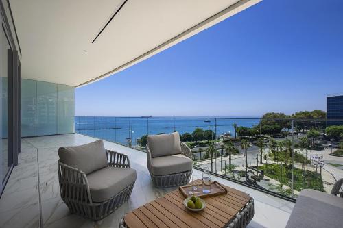 a living room with chairs and a table and a view of the ocean at Trilogy Limassol Seafront in Limassol