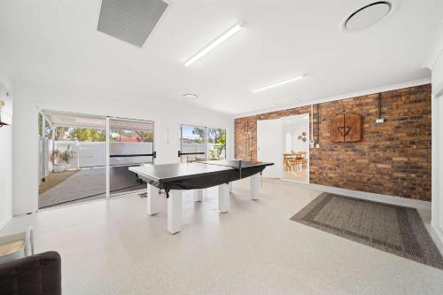 een woonkamer met een tafeltennistafel en een bakstenen muur bij Santai Sands - Bribie Island 4BD Home in Woorim