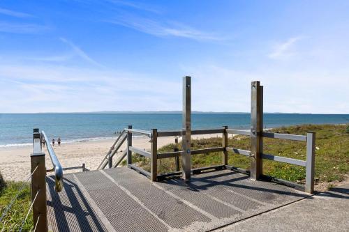 een promenade naar het strand met de oceaan op de achtergrond bij Santai Sands - Bribie Island 4BD Home in Woorim