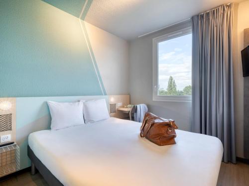 a hotel room with a bed with a purse on it at Ibis Budget Orly Chevilly Tram 7 in Chevilly-Larue