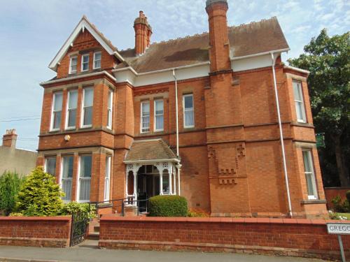 una vecchia casa in mattoni rossi con portico bianco di Holywell House a Loughborough