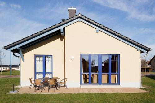 a white house with a table and chairs outside at Holiday home in Markkleeberg near a lake in Markkleeberg