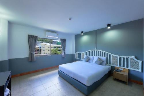 a bedroom with a white bed and a window at Nora Bukit Hotel in Ban Sam Kong