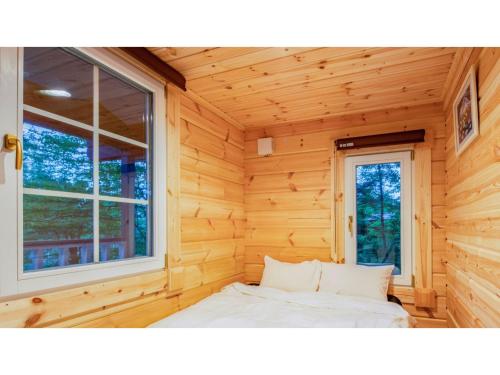 Bett in einem Blockhaus mit Fenster in der Unterkunft FARM SIDE - Vacation STAY 24170v in Tsumagoi