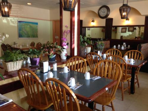 a dining room with tables and chairs and a clock at Sundre Motor Inn in Sundre