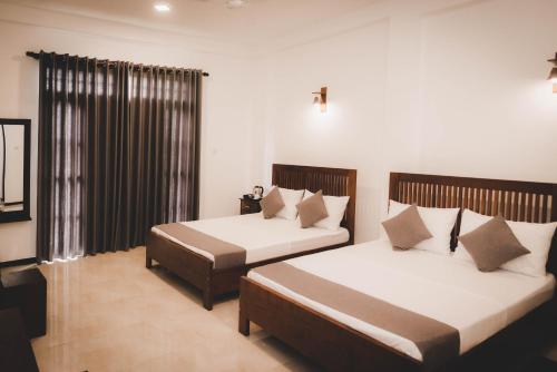 a bedroom with two beds and a window at Cinnamon Forest Villa - Private Luxury Villa in Hikkaduwa in Hikkaduwa