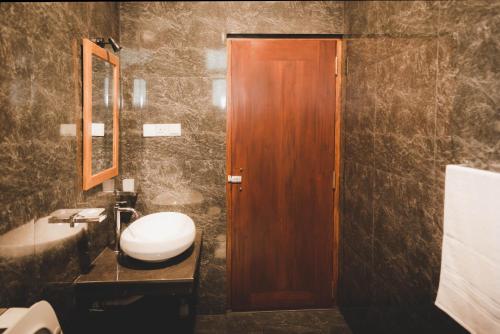 a bathroom with a sink and a wooden door at Cinnamon Forest Villa - Private Luxury Villa in Hikkaduwa in Hikkaduwa