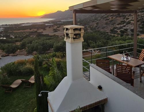 a house with a bird feeder on a balcony with the sunset at Casa di Olive, all seasons accommodation in Goúdhouros