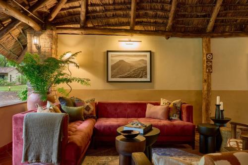 a living room with a red couch and a table at Rivertrees Country Inn in Usa River
