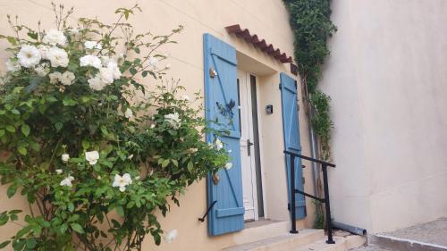 Una puerta y una ventana azules en un edificio con flores. en Petite pause à Pourrières, en Pourrières