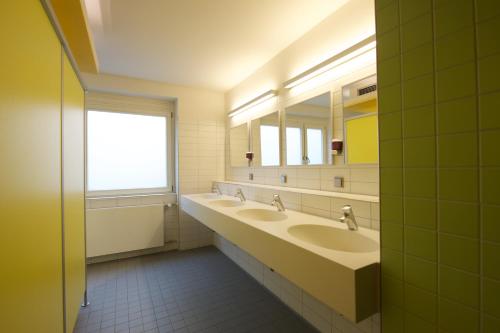 a bathroom with two sinks and a window at THE 4YOU Hostel & Hotel Munich in Munich