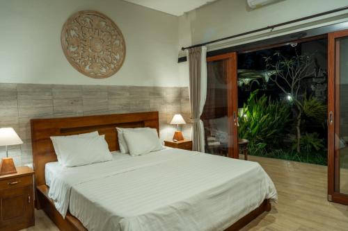 a bedroom with a bed with white sheets and a window at Bali Vanili Villa in Sukawati