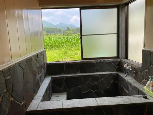 a bathroom with a large stone tub with a window at 絶景cottage 1棟貸切り 星空B棟 in Anazawa