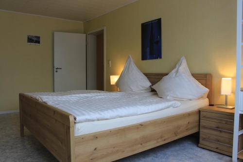 a bedroom with a wooden bed with white pillows at Weingut Gorges-Reinhard in Wintrich