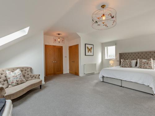 a bedroom with a bed and a couch and a chandelier at 3 Bed in Barnstaple 87116 in Fremington