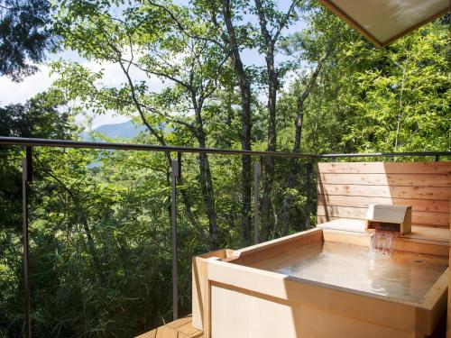 a hot tub on a deck with trees in the background at Hakone Retreat villa 1/f in Hakone