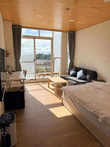 Un dormitorio con una cama y una ventana grande. en 雲山盼盼民宿, en Dongshi