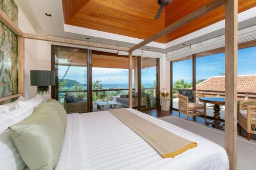 ein Schlafzimmer mit einem großen weißen Bett und einem Balkon in der Unterkunft Katamanda Villa Allegra 5 bedroom Seaview villa in Kata Beach