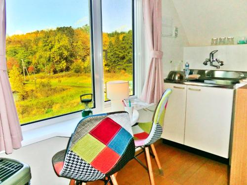 a kitchen with a table and chairs and a window at 丘の上白亜の洋館風別荘静かな小さなお宿 3階屋根裏部屋ロフトタイプ 3ベッドルームキッチン洗濯機なし in Asahikawa