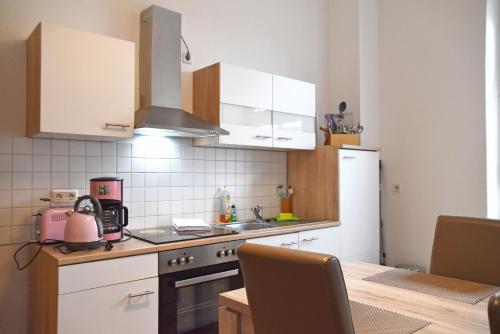 a kitchen with a sink and a stove and a table at GUWO Gästewohnung Straupitzstraße 12 in Guben