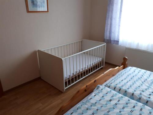 UtarpにあるNEU! Ferienwohnung Tideのベッド2台、ベビーベッド1台、窓が備わる客室です。