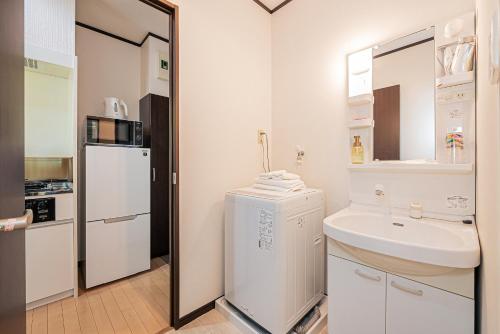 a white bathroom with a sink and a refrigerator at Japan House Oshiage in Tokyo