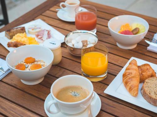 una mesa de madera con tazas de café y productos para el desayuno en Mercure Figeac Viguier du Roy, en Figeac