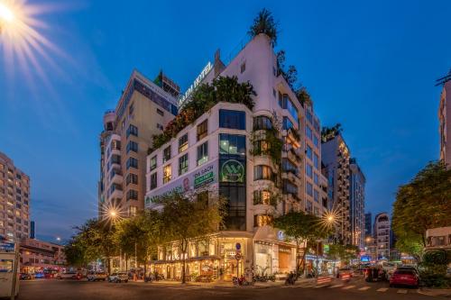 ホーチミン・シティにあるA&EM アート ホテルの木々が立ち並ぶ高い白い建物