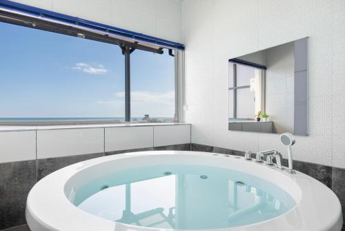 a bath tub in a bathroom with a large window at Yeongdeok Searest Pool Villa in Changsa-ri