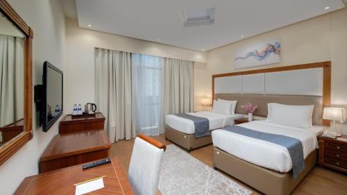 a hotel room with two beds and a desk at Vendome Plaza Hotel in Dubai